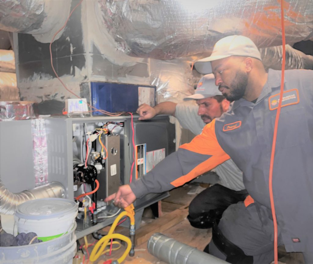 Two men operating an industrial furnace, working attentively among heavy machinery and equipment, showcasing precision and safety in furnace operation.