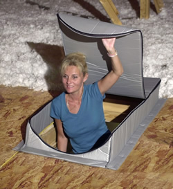 Person emerging from a small insulated attic hatch surrounded by insulation and wooden flooring, highlighting attic access and sealing with Attic Tents.
