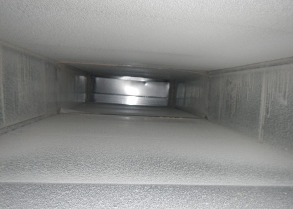 Looking up inside a metallic air duct with smooth, clean surfaces and faint condensation marks, highlighting the importance of duct replacement and maintenance.